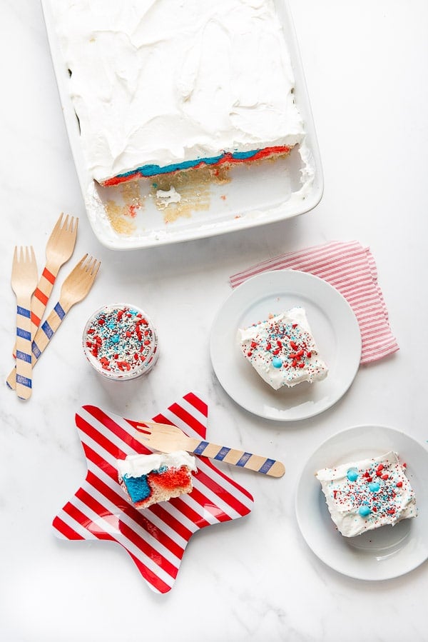 Red White and Blue Cake with whipped cream and sprinkles on a red striped plate