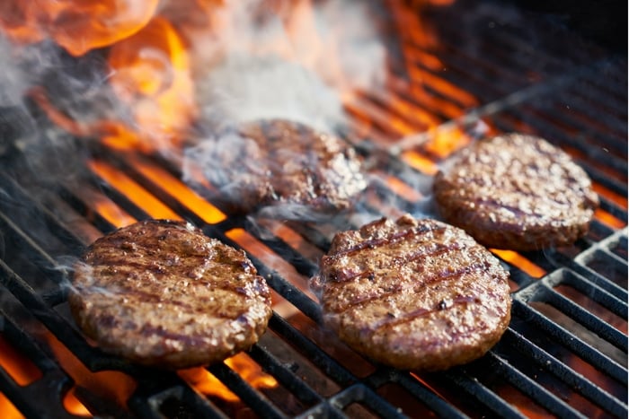 Burgers cooking on grill with grill marks and fire