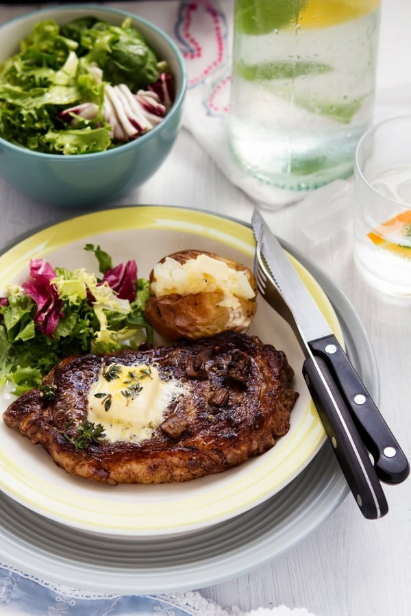 herb butter for steak on a plate with salad and potato