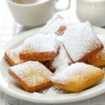 New Orleans food: Beignets on a white plate with coffee and cream