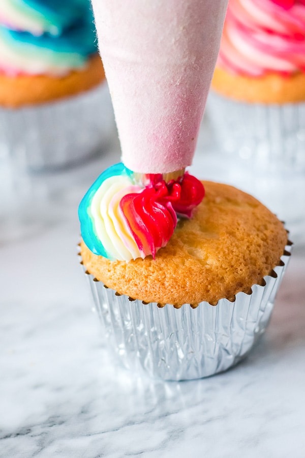 piping red white and blue frosting on a cupcake