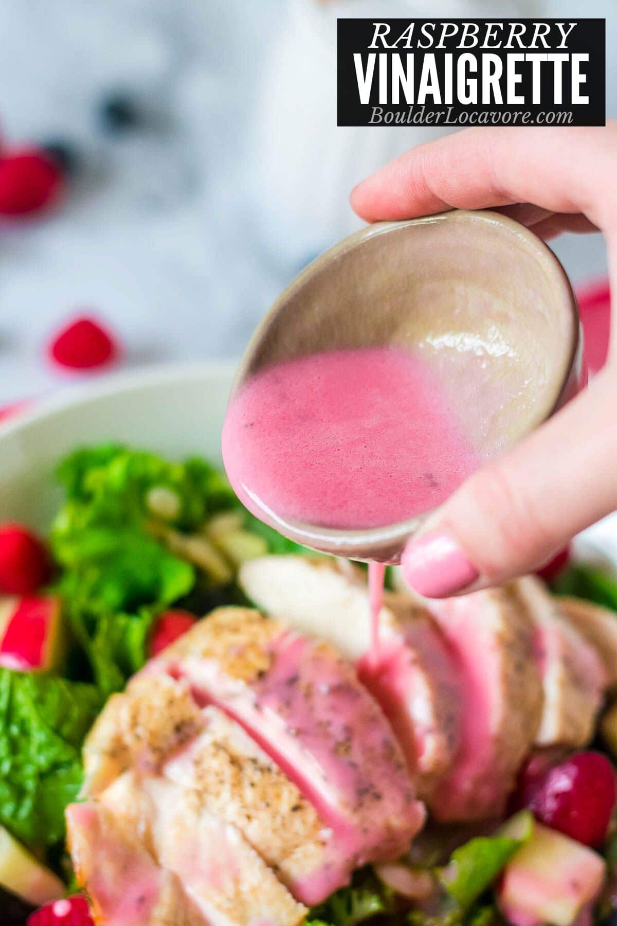 raspberry vinaigrette in bowl pouring onto salad.