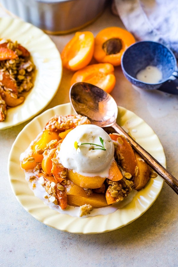 Serving of apricot crumble with vanilla ice cream on a vintage plate