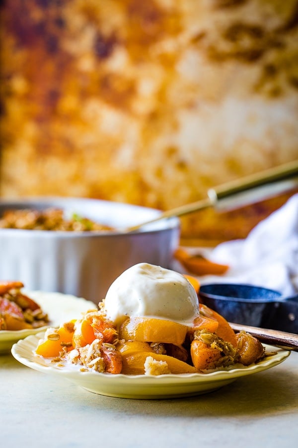 side view of warm apricot crumble with vanilla ice cream on top