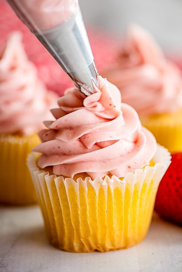 frosting a cupcake with strawberry icing