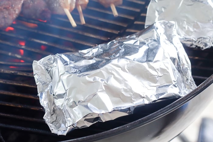 grilled potatoes wrapped in foil on grill 