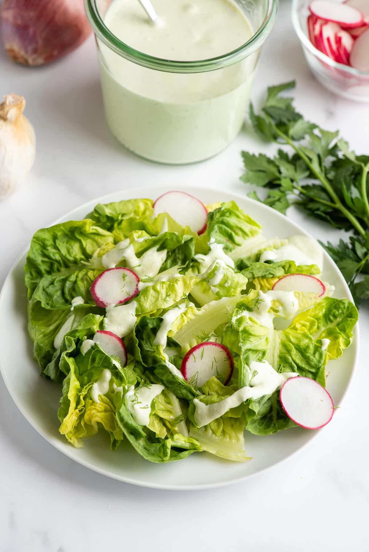 Green Goddess Dressing on a fresh lettuce salad on a white plate