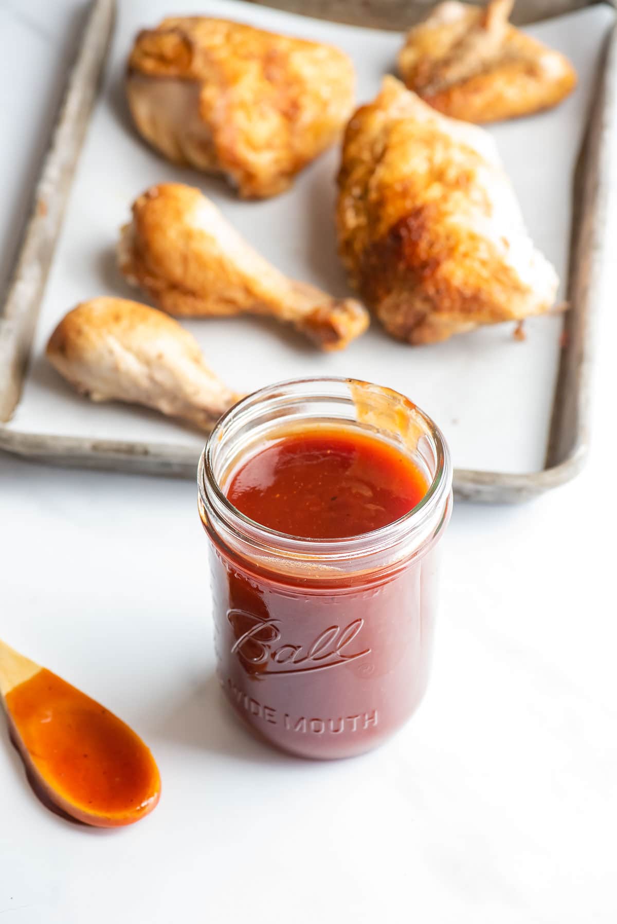 barbecue sauce in jar with chicken in background