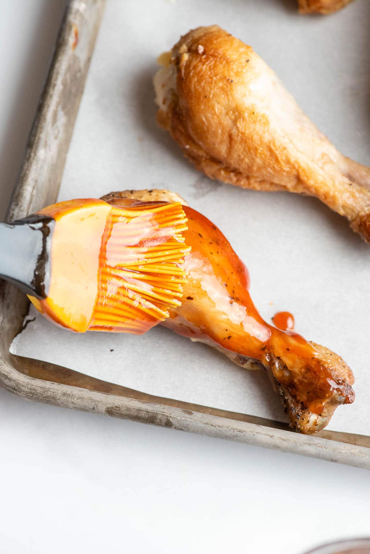 brushing barbecue sauce on a chicken drumstick