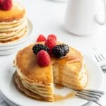 stack of fluffy buttermilk pancakes on a white plate with wedge cut out