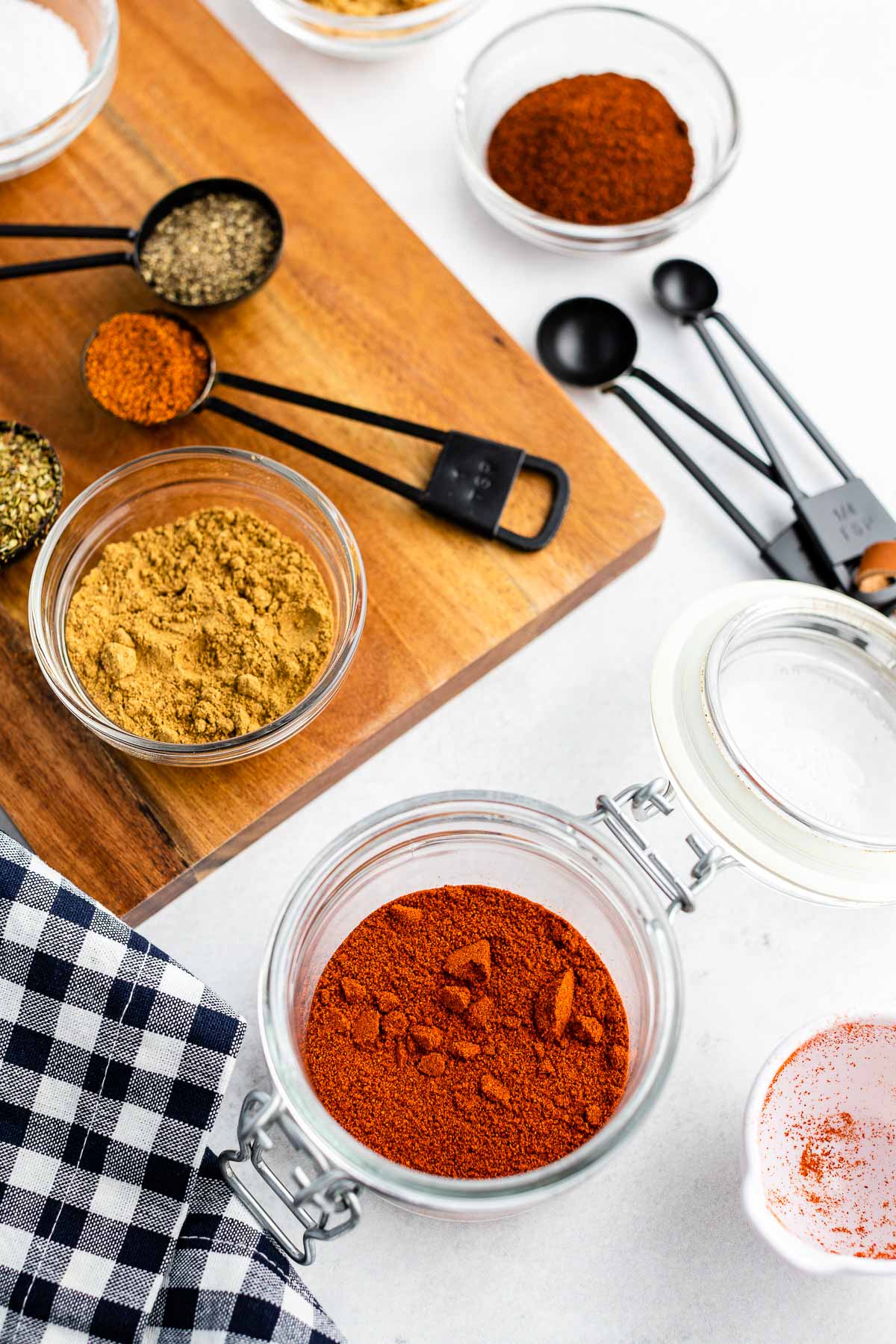 mixing dry rub in a jar with measured out spices in the background