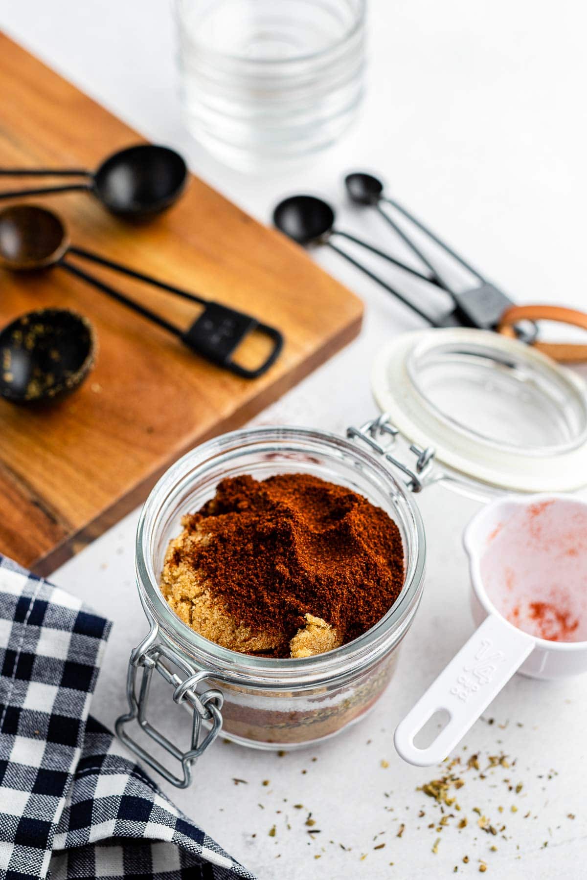 homemade dry rub being mixed in a jar with measuring spoons in the background