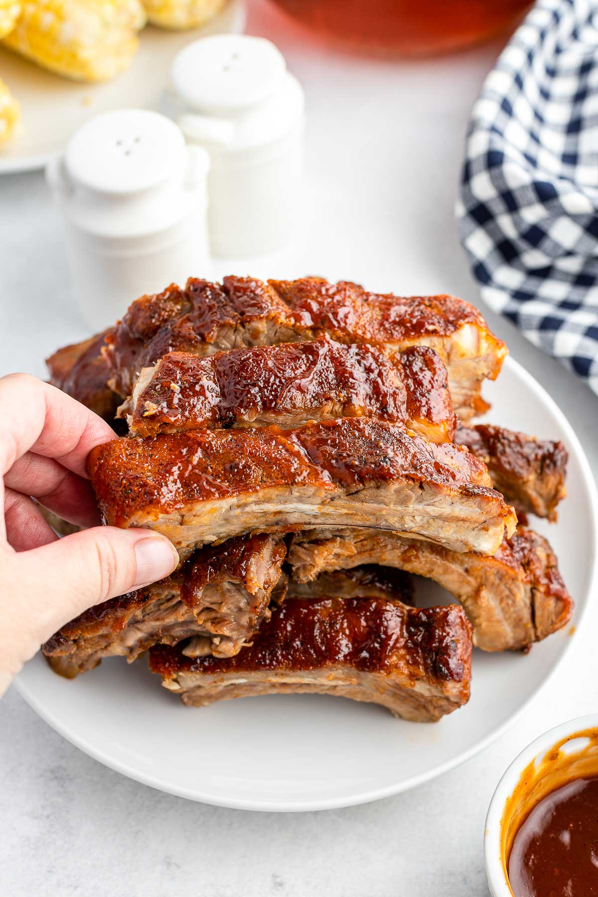 oven baked ribs on a plate with hand holding a rib