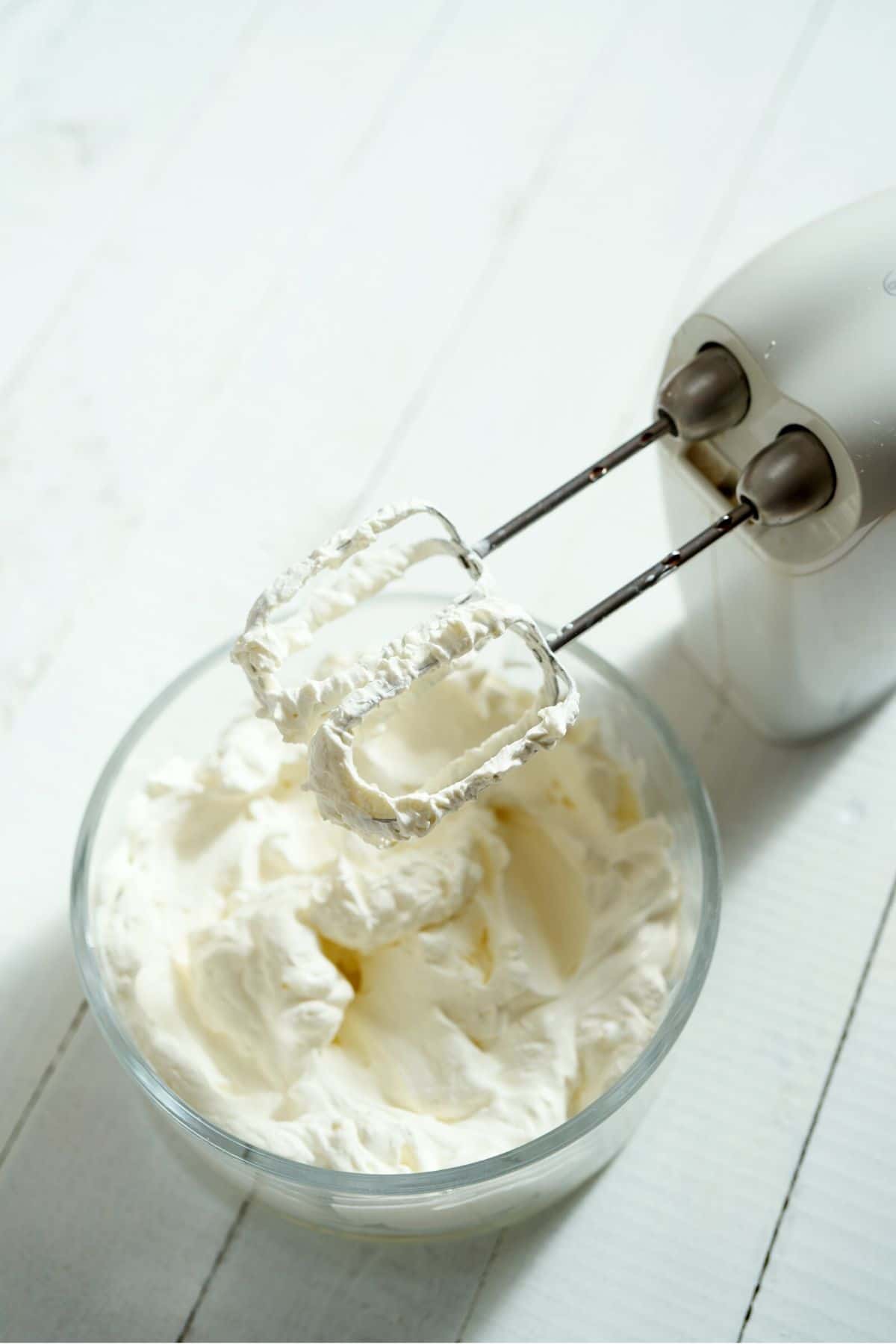 whipped cream in a glass bowl with hand mixer