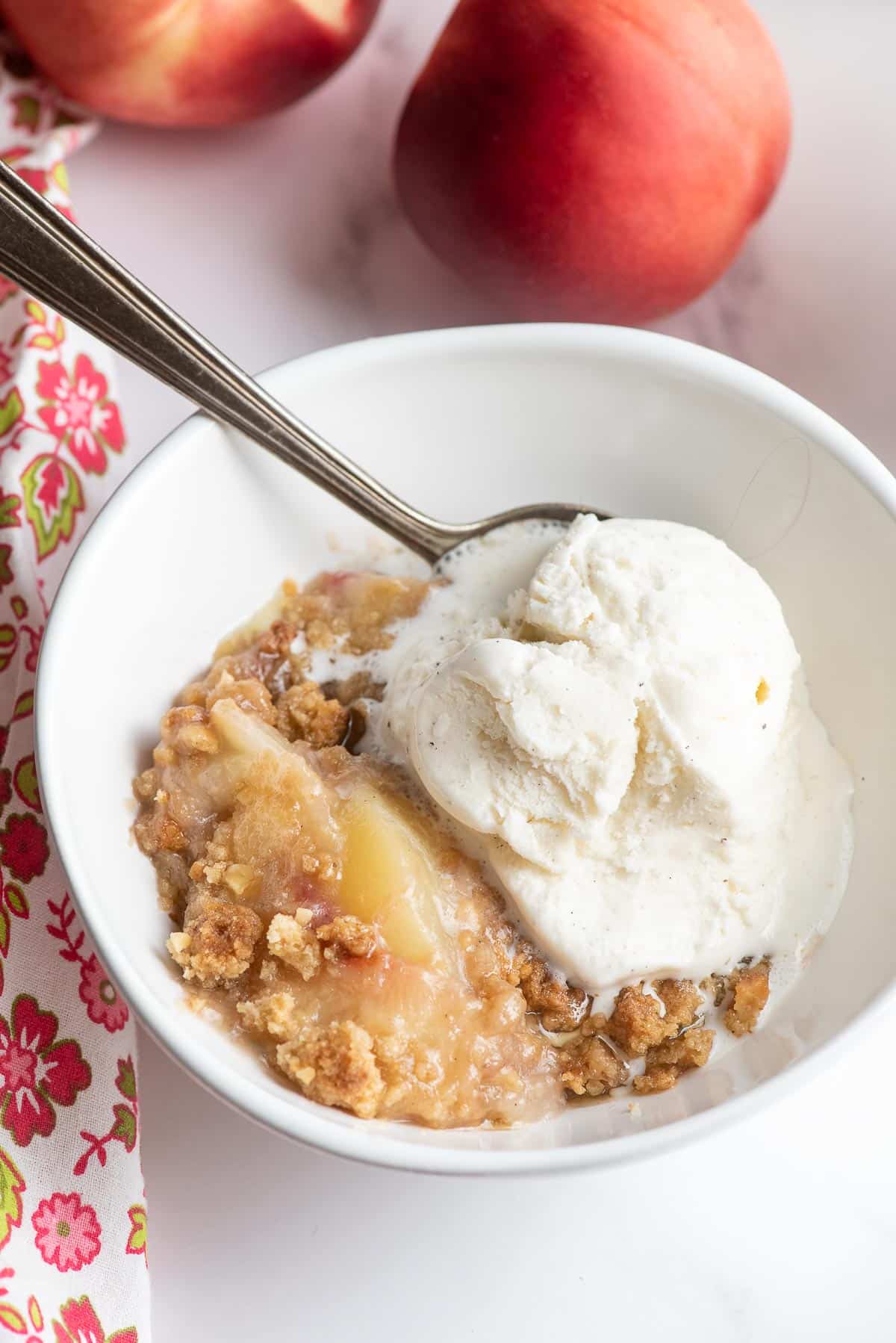 cooked peach crumble in a bowl with ice cream
