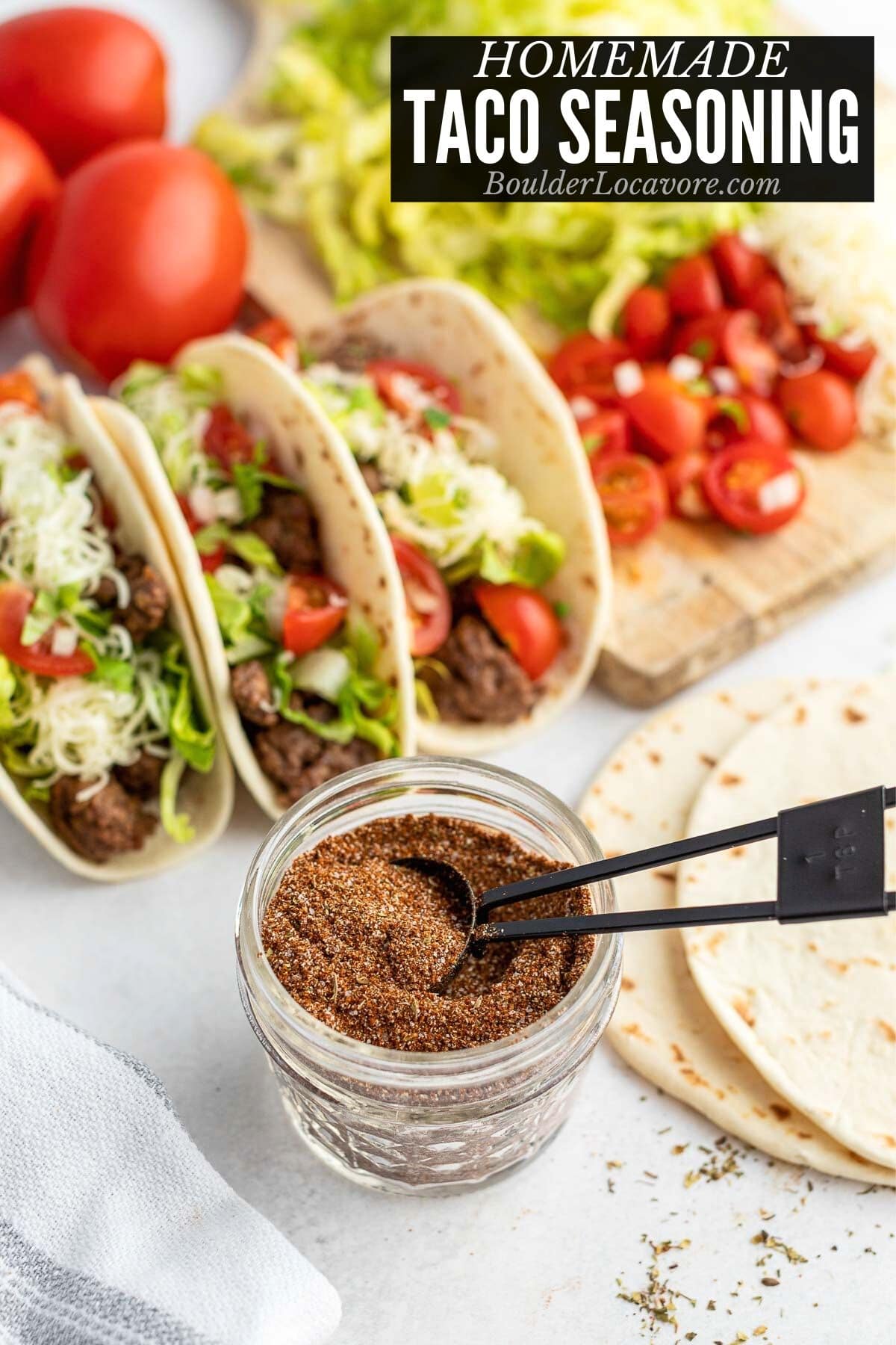 homemade taco seasoning in a small jar with tacos behind