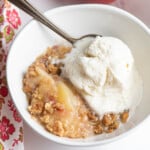 peach crumble in bowl with ice cream .