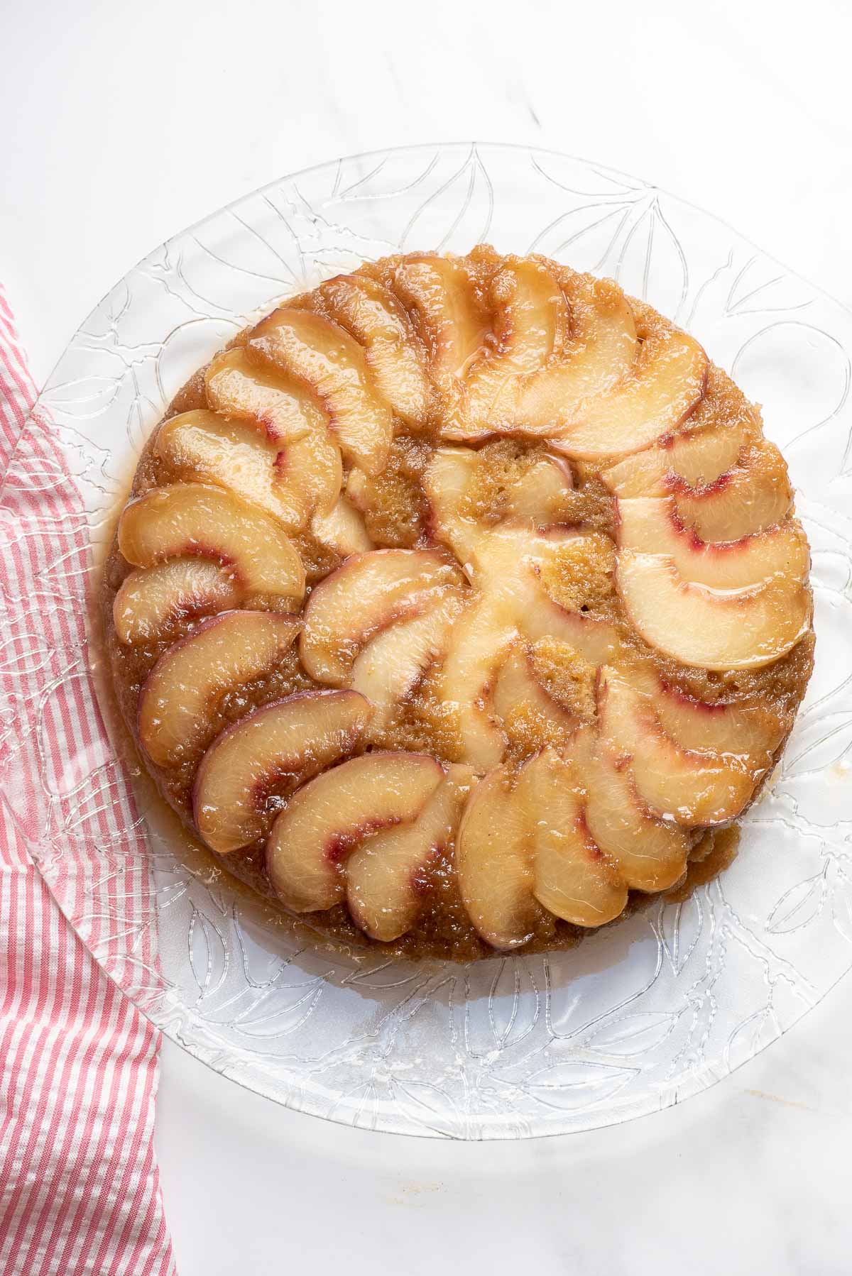 peach upside down cake on serving platter and cloth