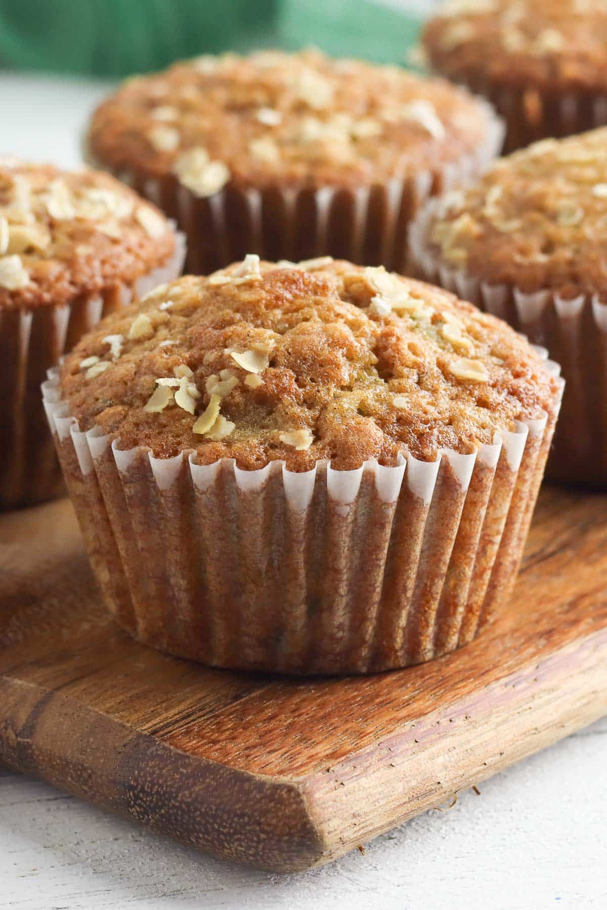 single zucchini muffin on wood cutting board