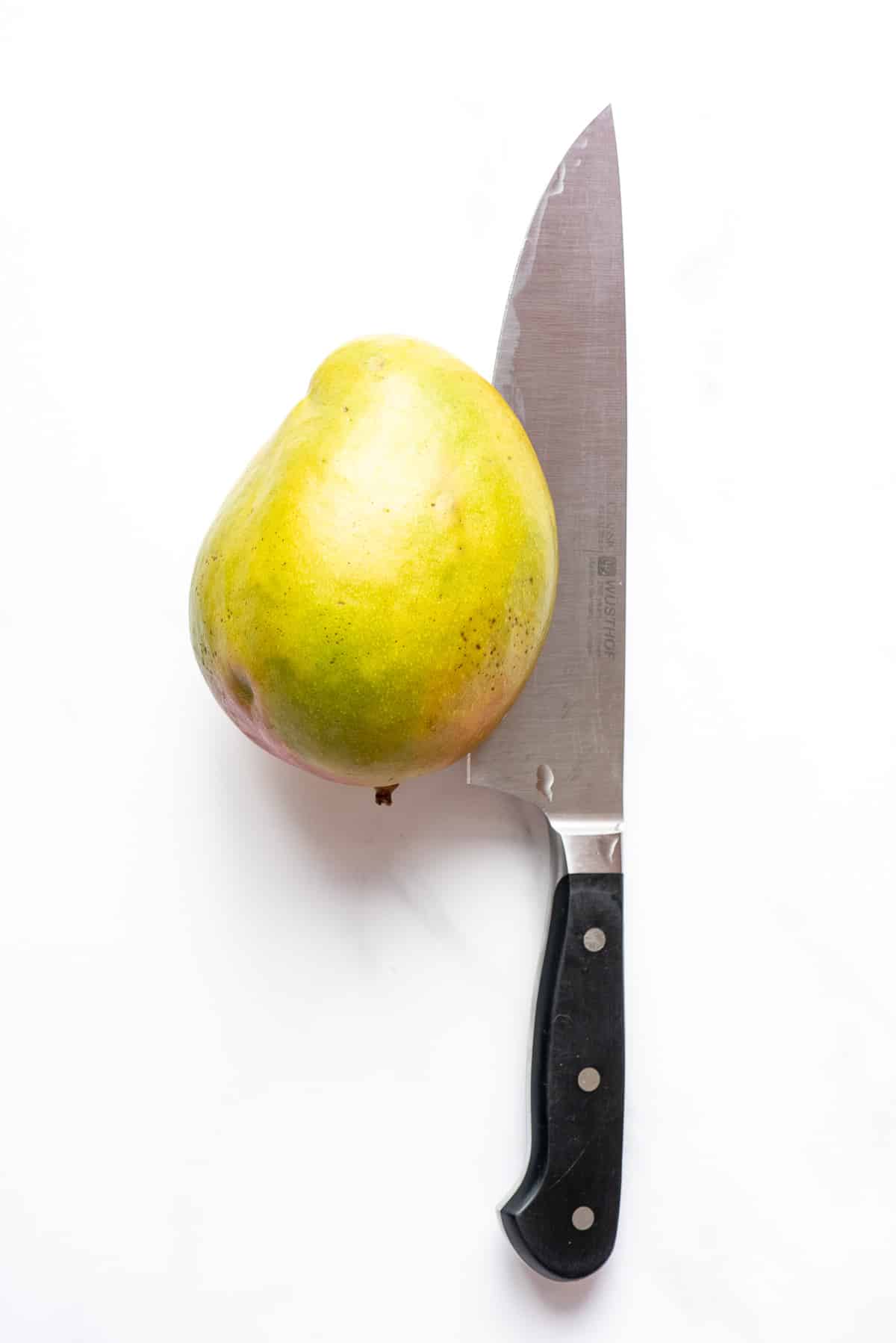 cutting through a mango with a large knife