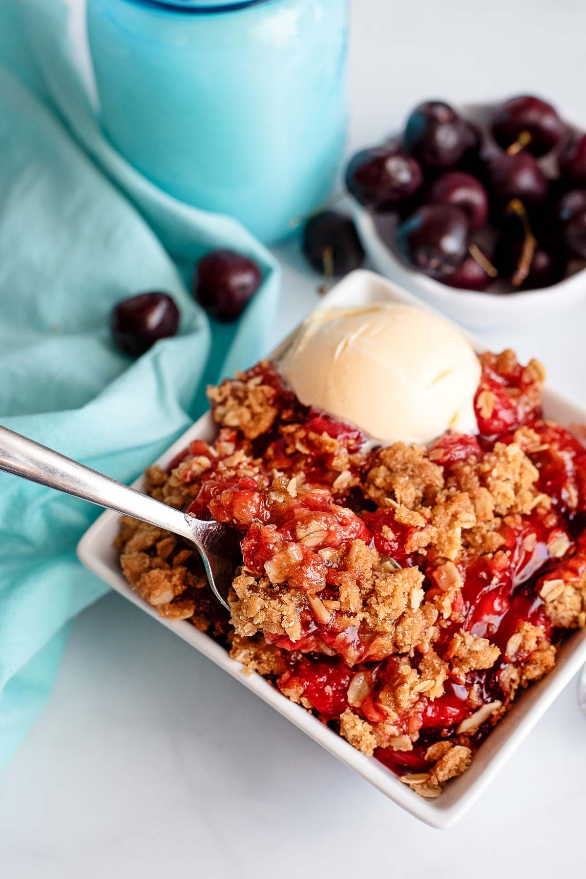 cherry crisp serving in bowl with spoon 