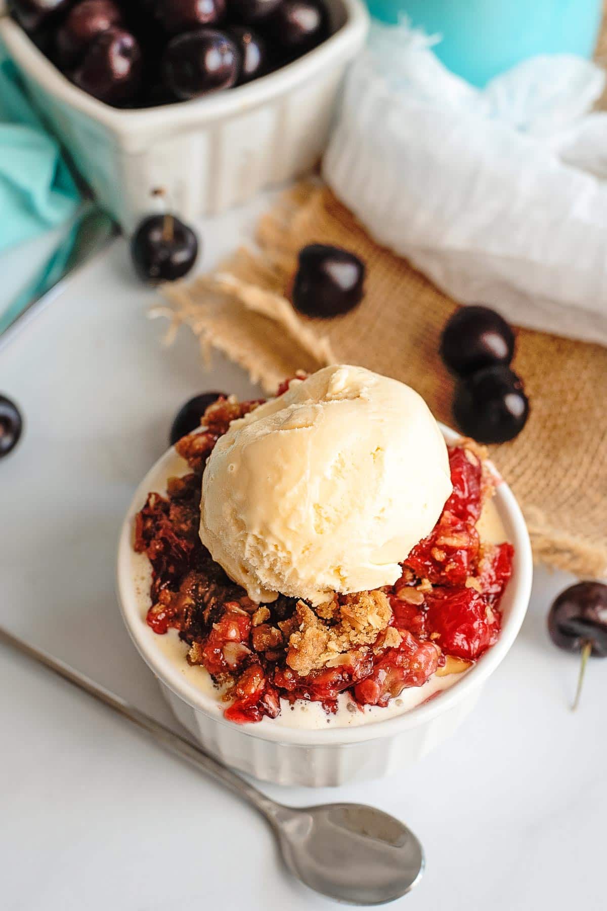 cherry crisp serving with cherries in background ice cream spoon 