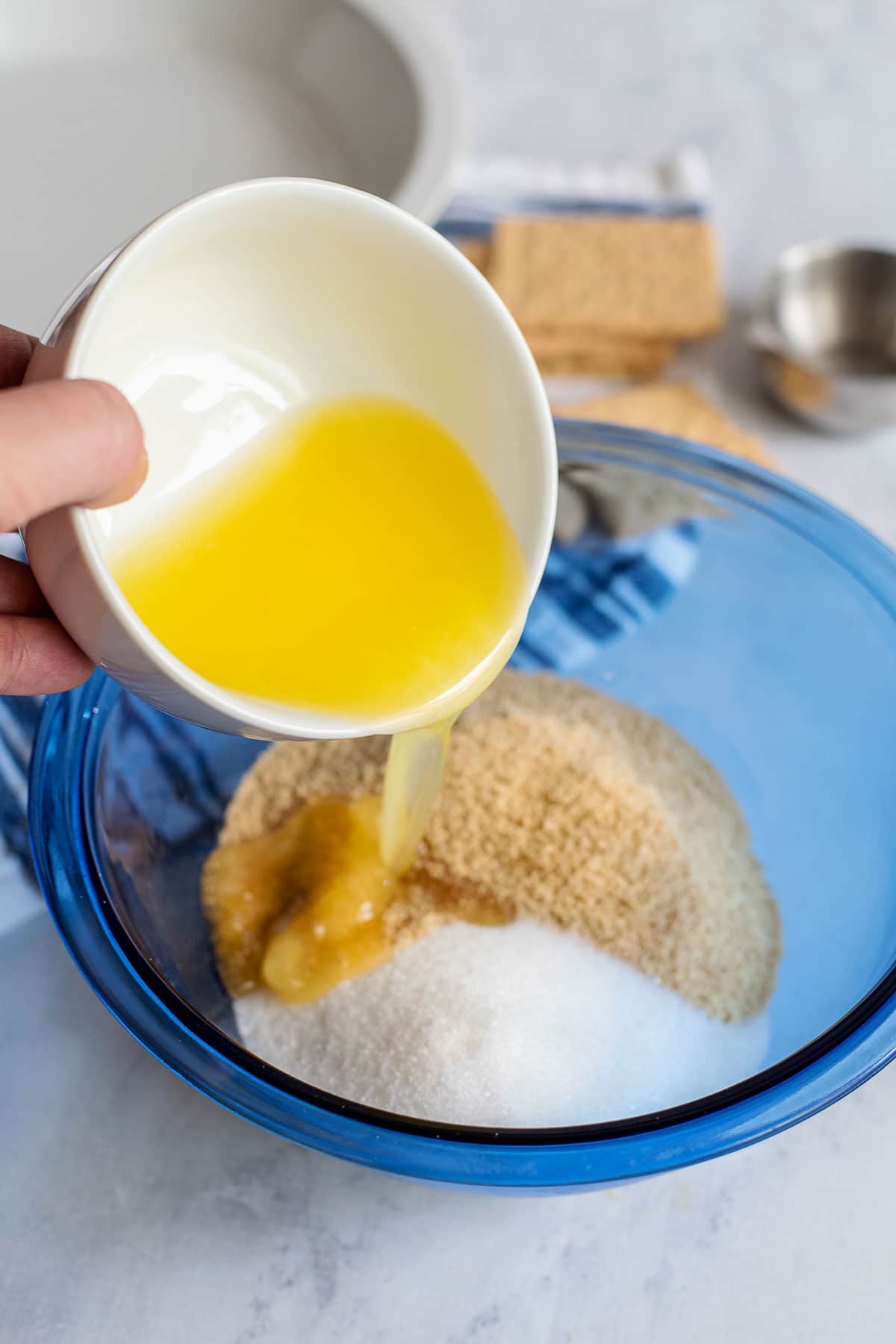 pouring melted butter into graham cracker pie crust ingredients