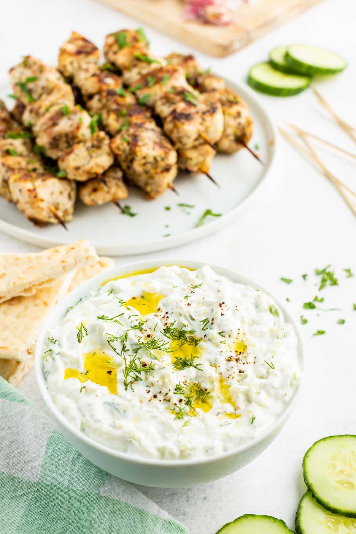 tzatziki sauce with chicken souvlaki skewers in the background