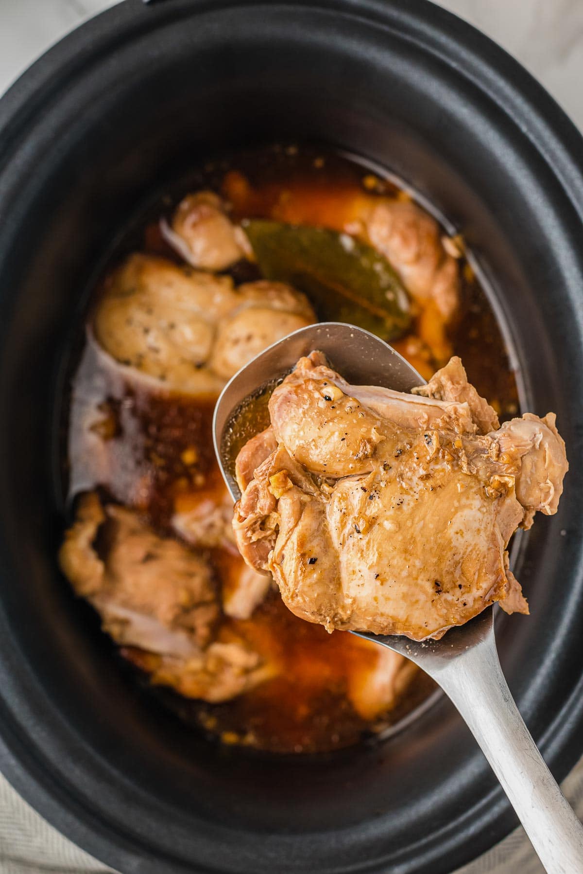 chicken adobo cooked in slow cooker on spoon