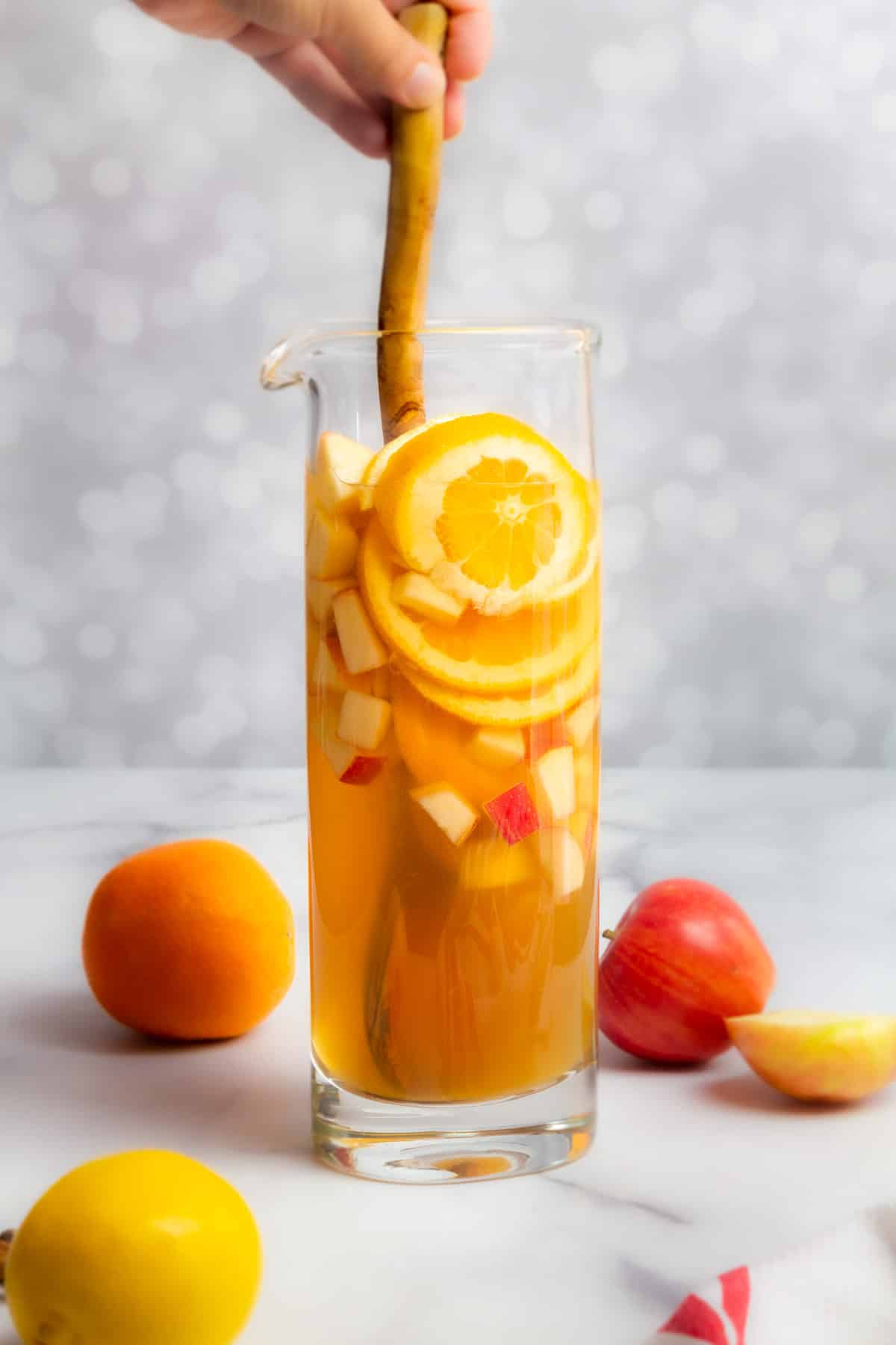 apple cider sangria in pitcher stirring