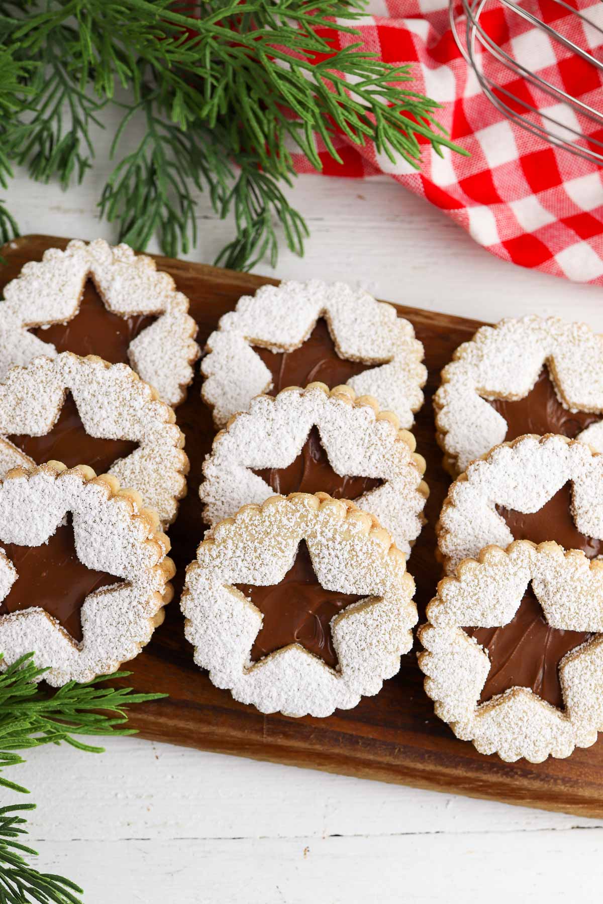 stacked Linzer cookies with evergreen sprigs