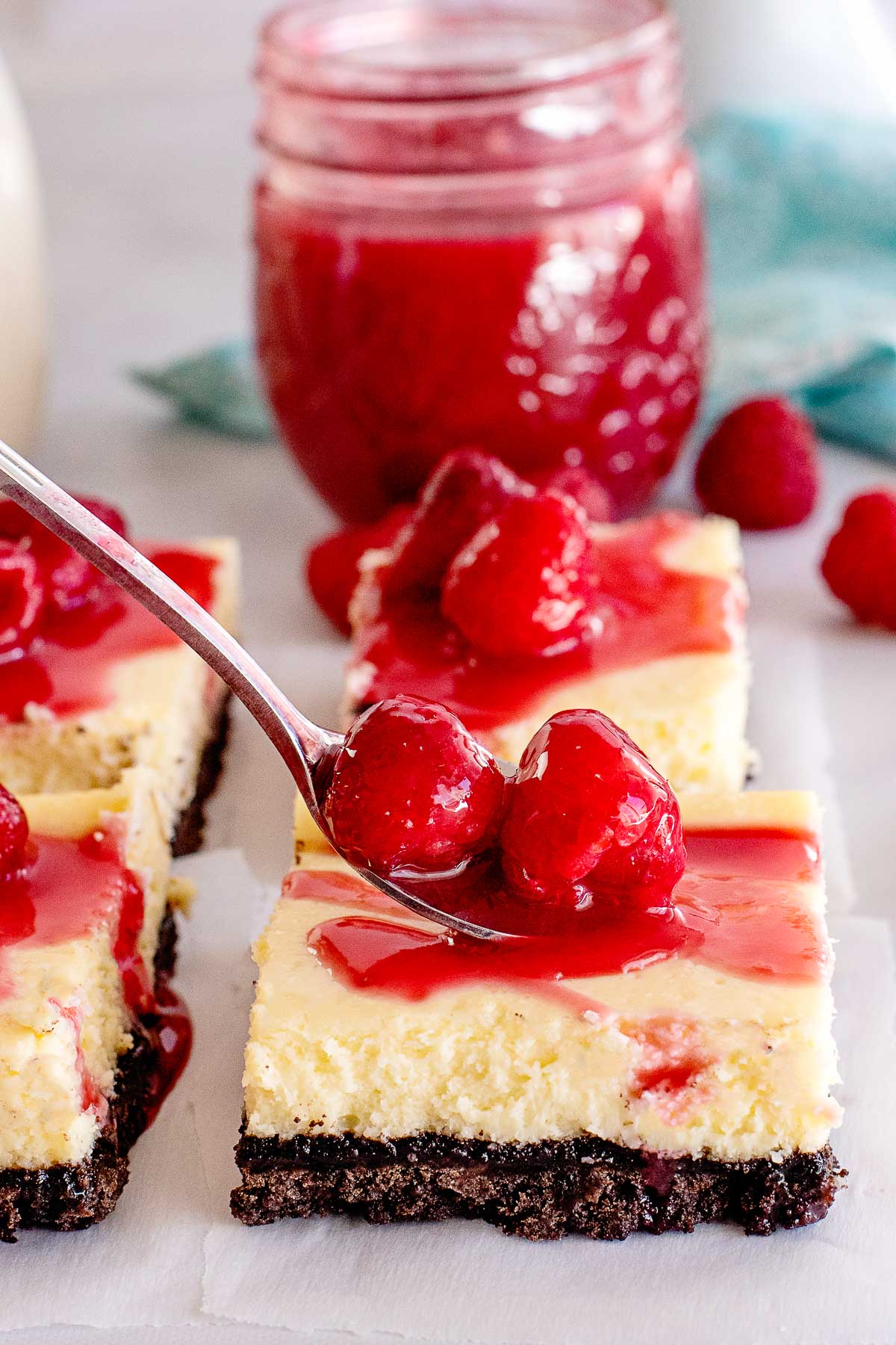 raspberry sauce in jar on cheesecake bars.