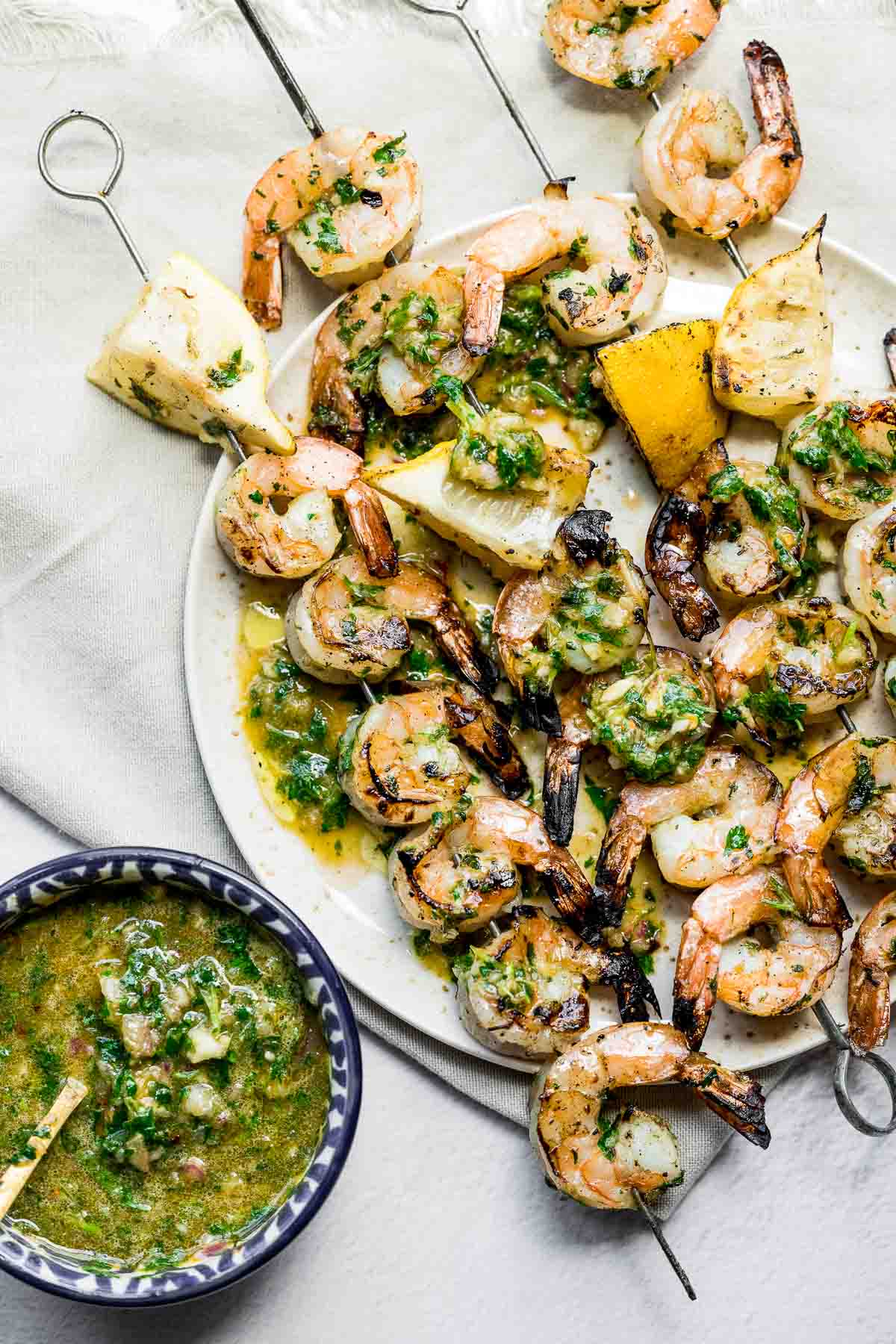 platter of grilled shrimp skewers with chimichurri sauce.