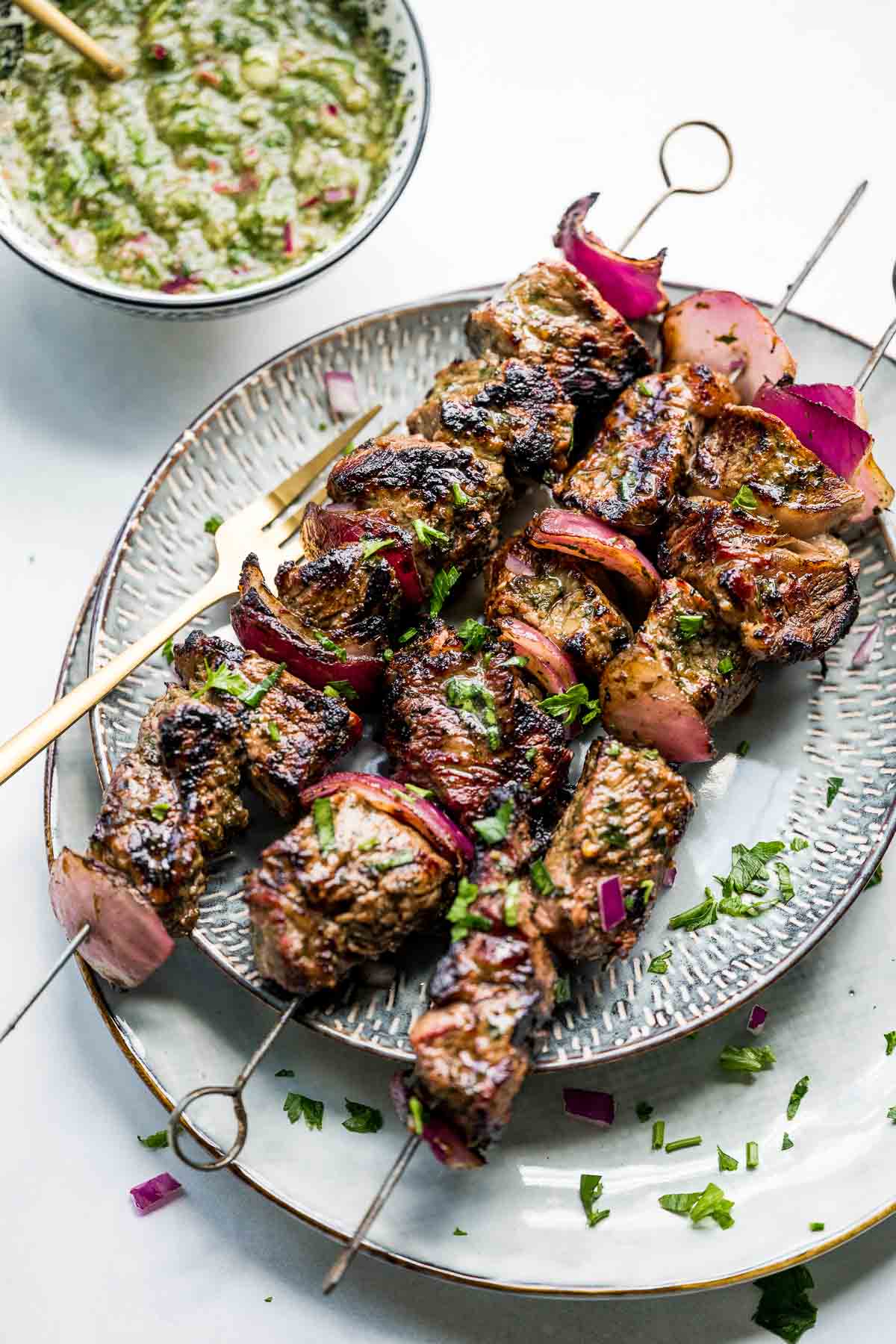 chimichurri steak skewers on plate with sauce.