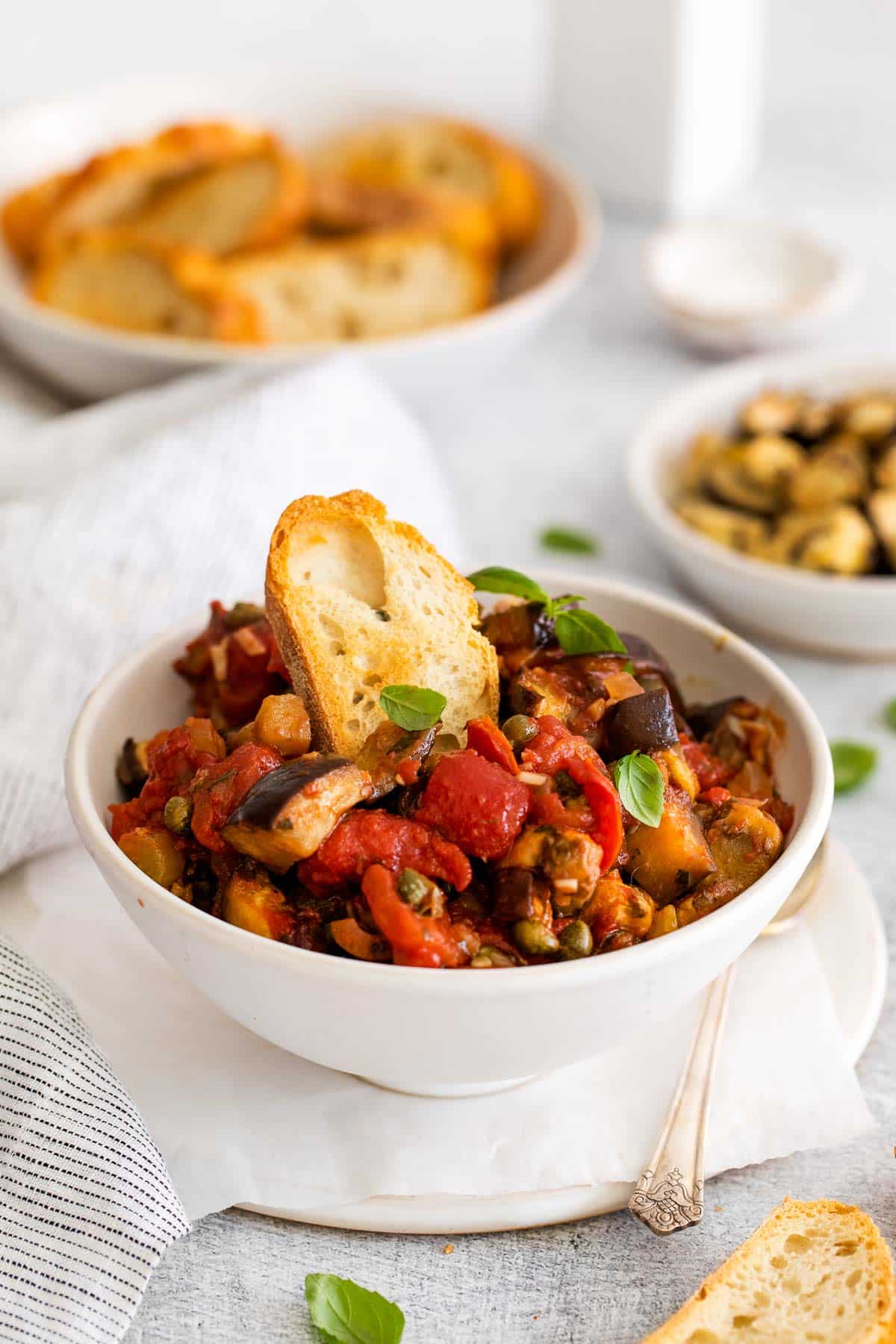 eggplant caponata in a bowl with baguette slice.