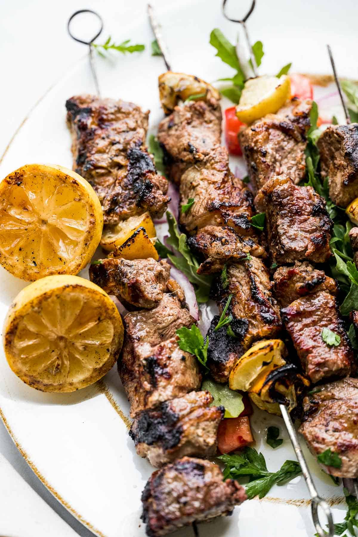 greek steak kebabs on plate with grilled lemons.