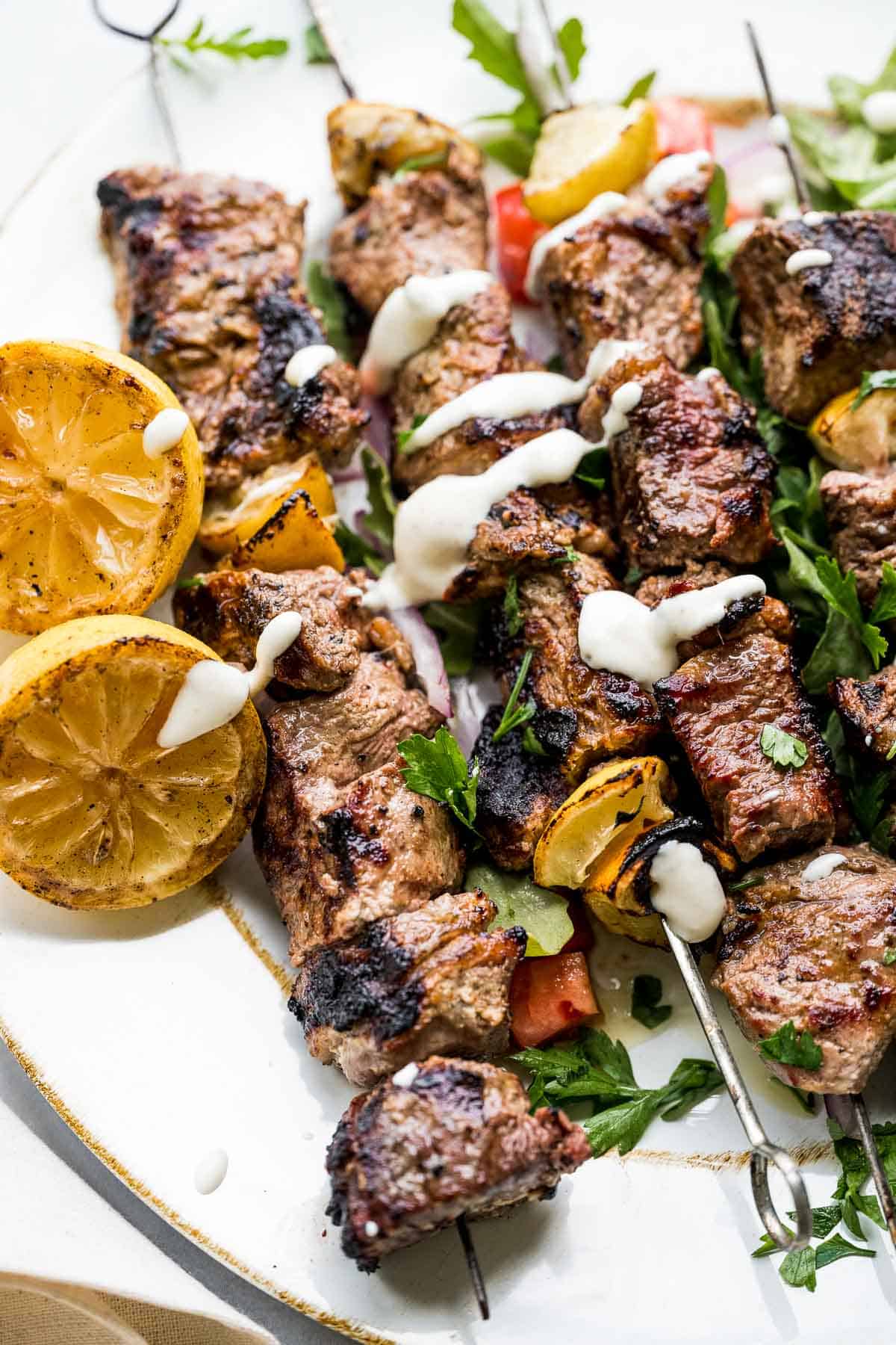 greek steak kebabs with yogurt dipping sauce and lemons.