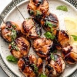 grilled scallops on skewers on plate with lemon.