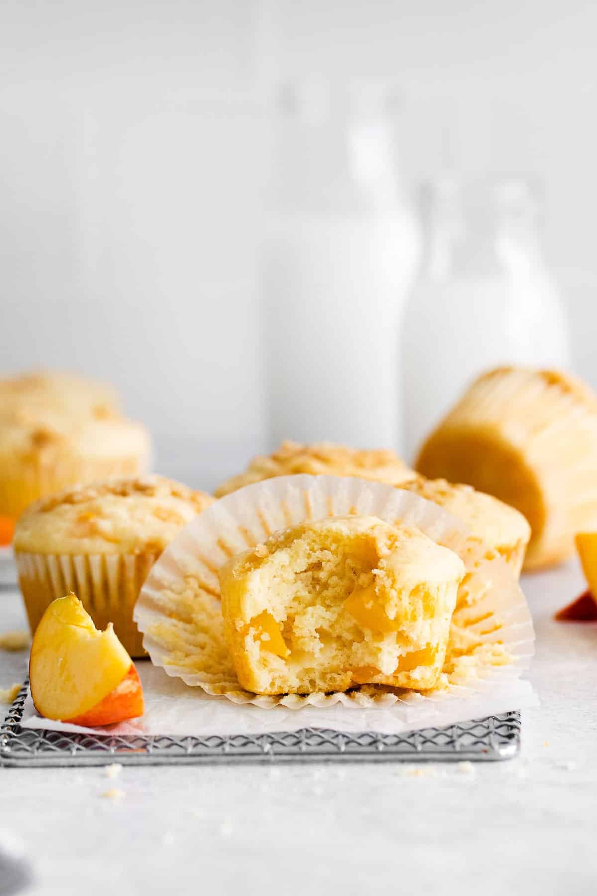peach muffins on wire rack with bite.