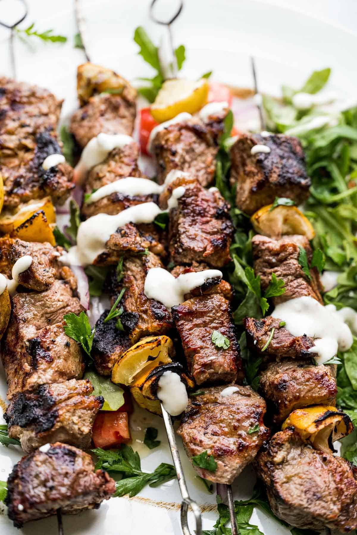plate of greek steak kebabs with yogurt dipping sauce close up.