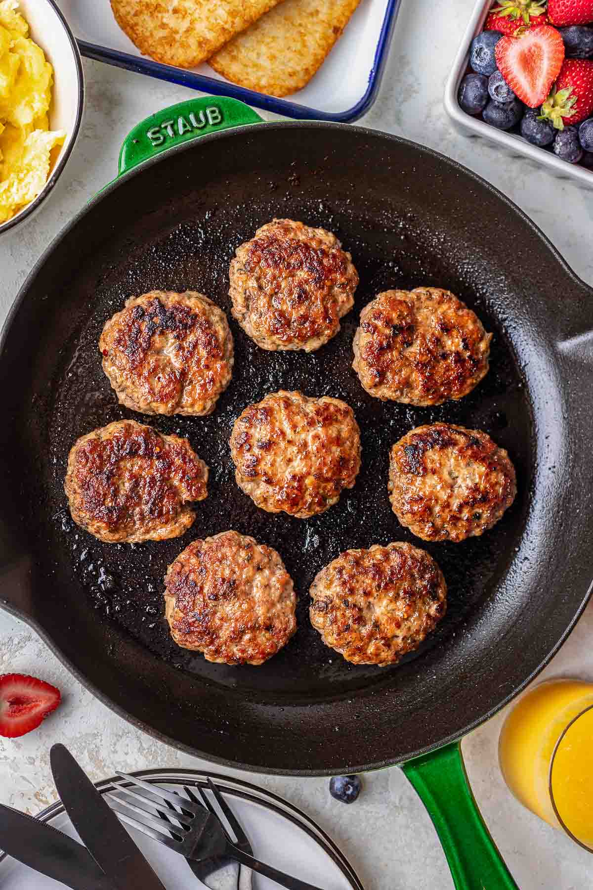 homemade breakfast sausage patties in green skillet with breakfast food close up.
