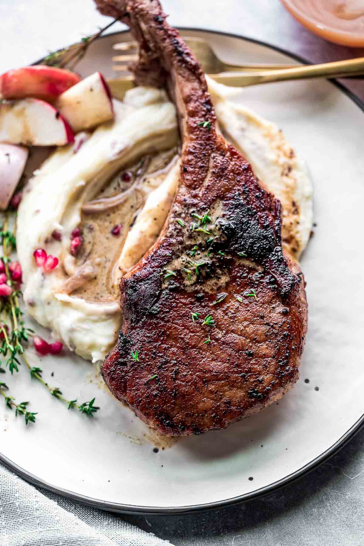 pan seared pork chop on plate with mashed potatoes.