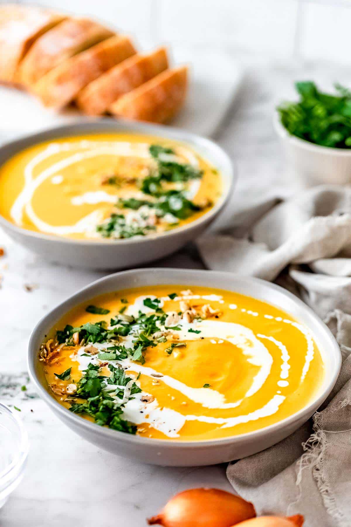slow cooker pumpkin soup in bowls with garnish.