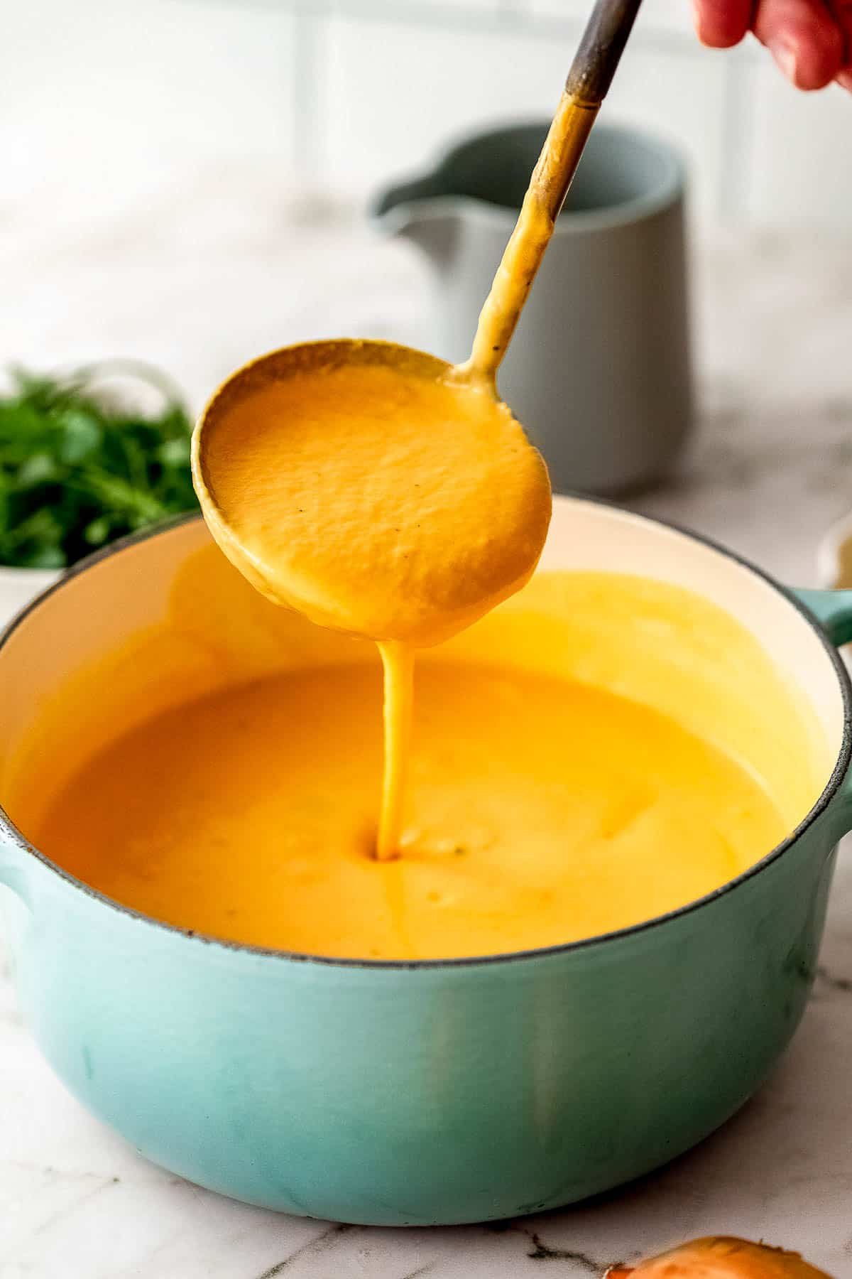 slow cooker pumpkin soup with ladel in stock pot.