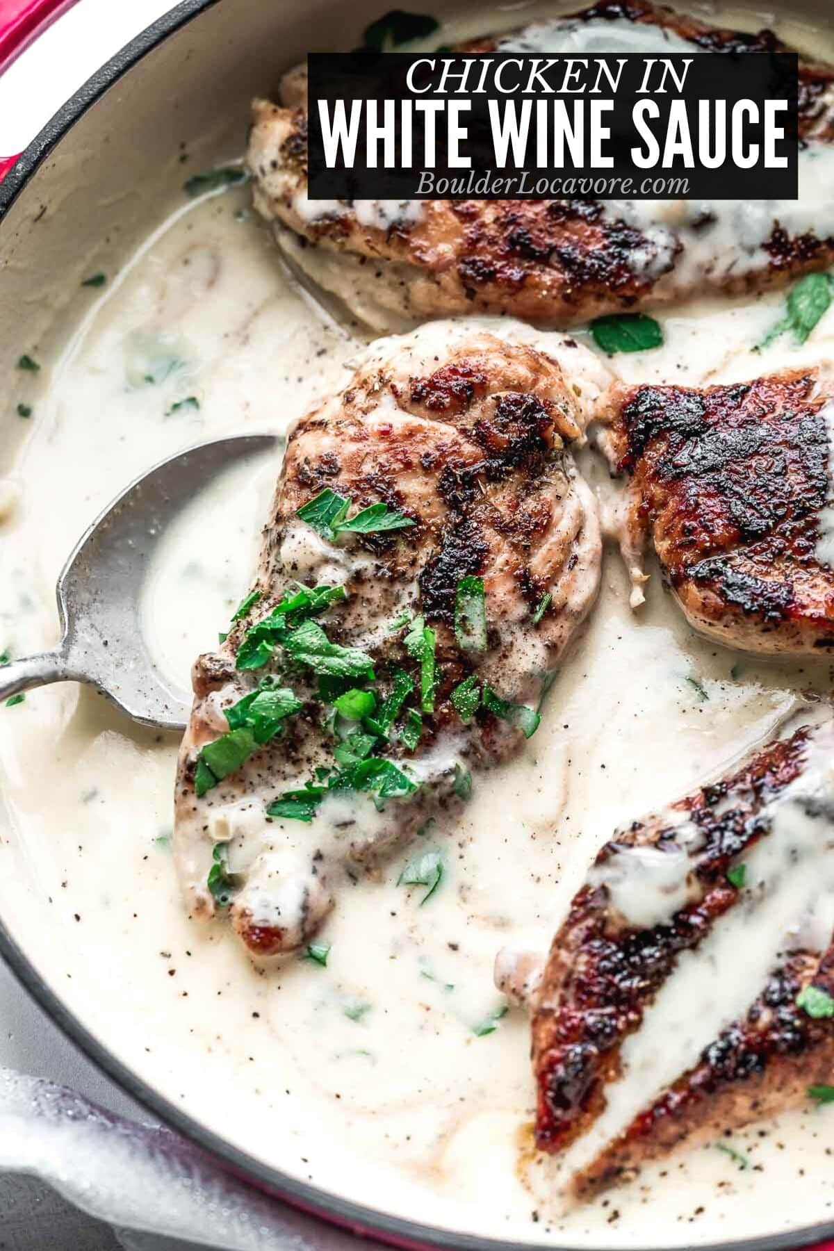 chicken in white wine sauce in pan with spoon.