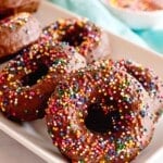 chocolate frosted donuts on a white serving plate.