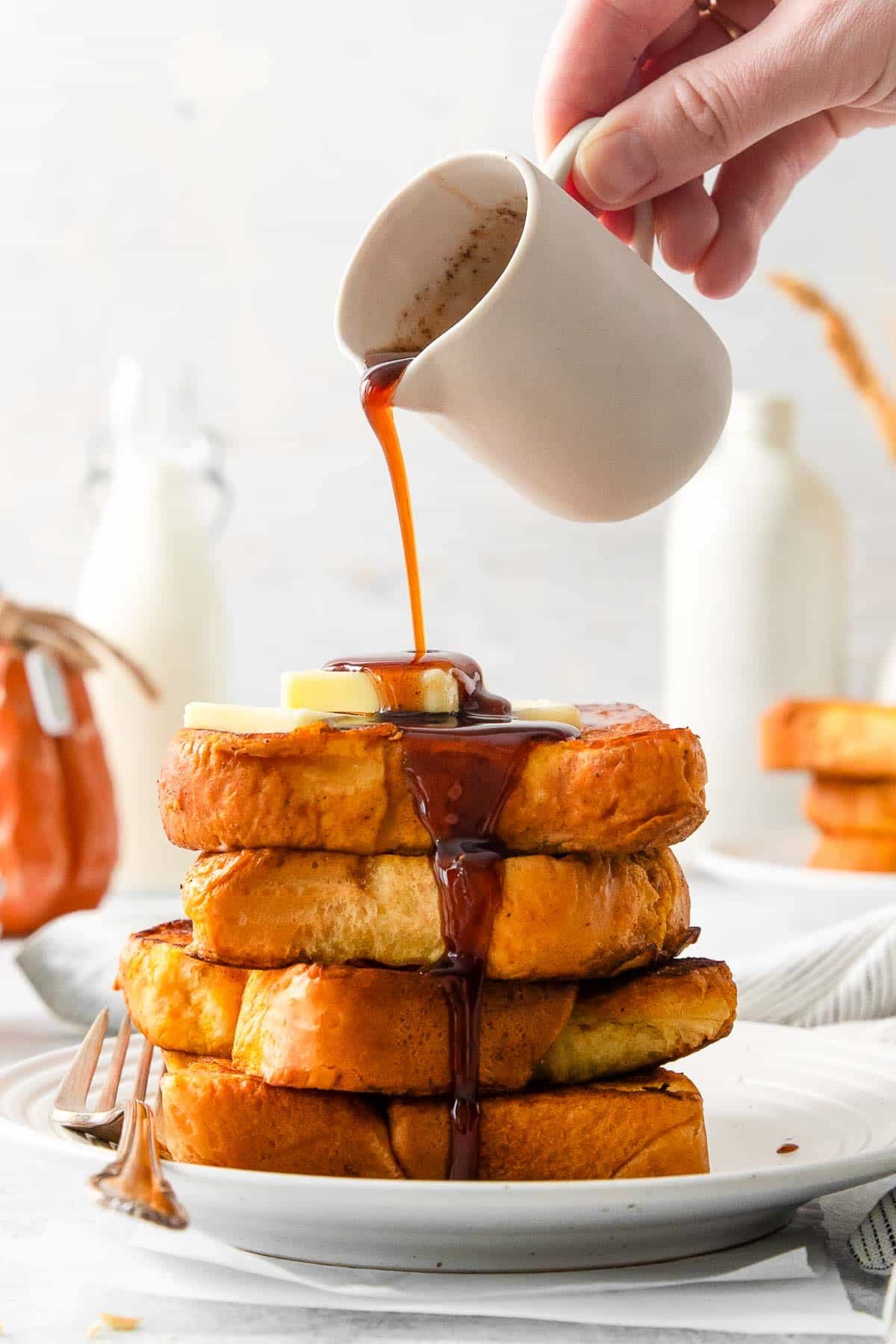 pumpkin french toast on plate with syrup pouring side view.