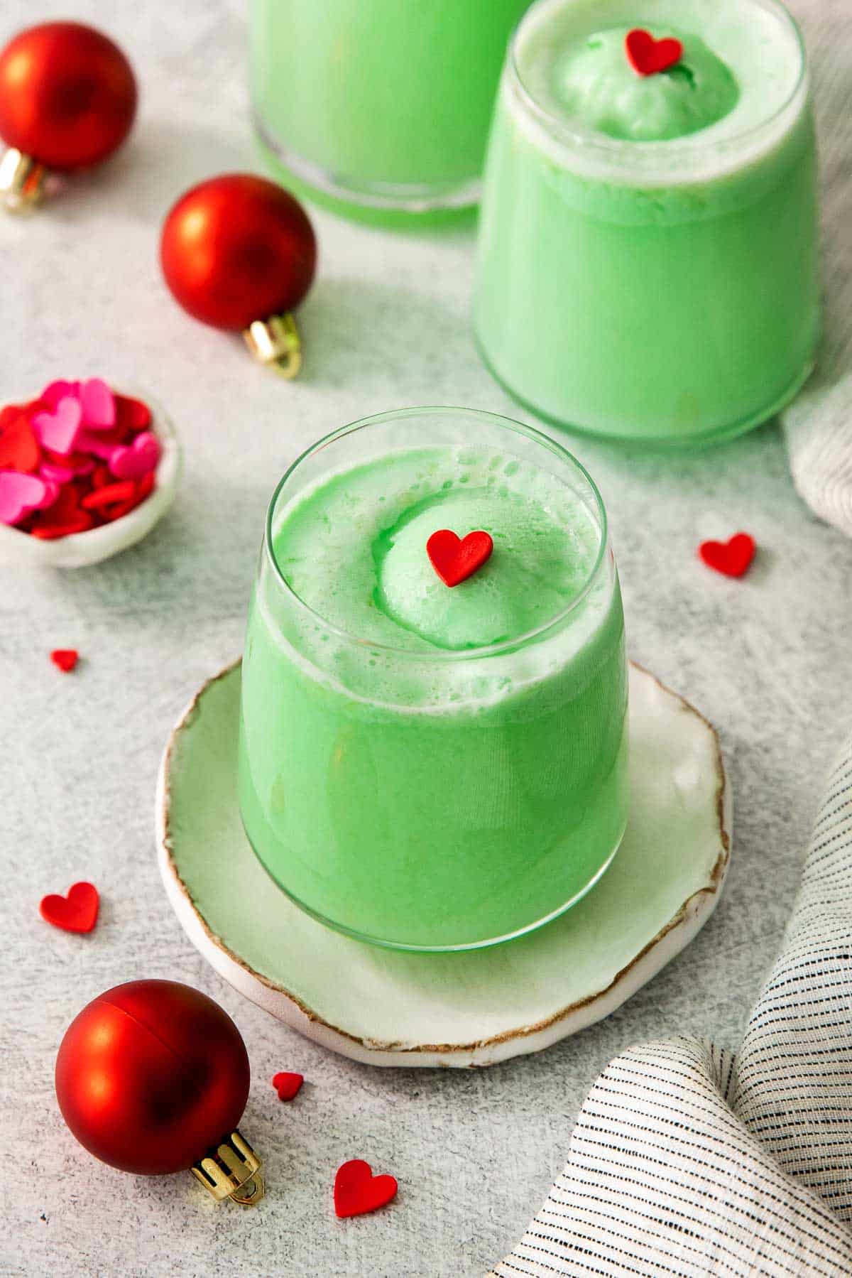 grinch punch in glasses with red hearts overhead.