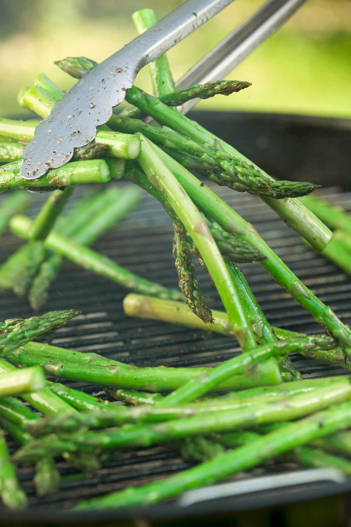 asparagus on grill being flipped by tongs