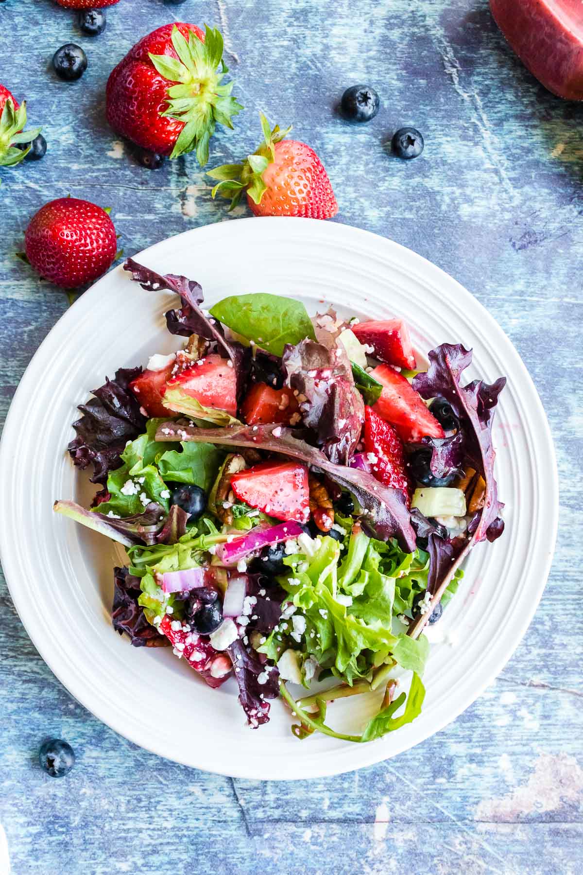 tossed fresh strawberry salad on a white plate